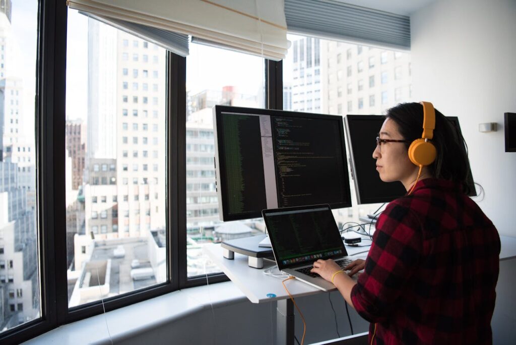 A software developer working on multiple monitors with code, highlighting the workflow of a Flutter app development company creating cross-platform mobile applications.