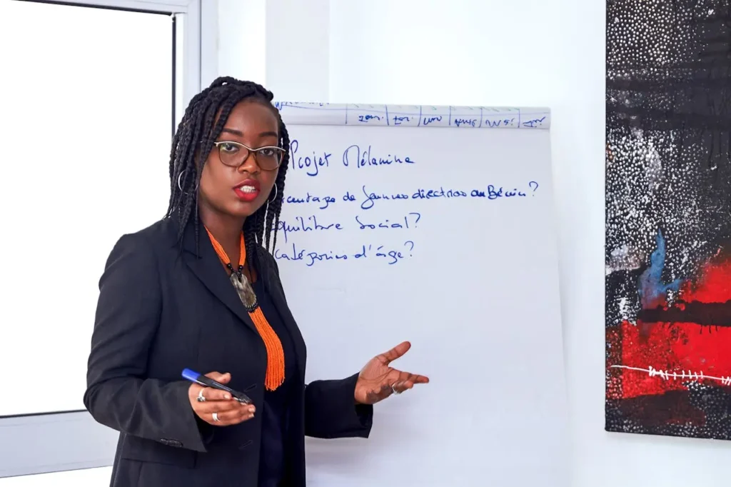 Businesswoman giving a presentation beside a whiteboard with handwritten notes on app development strategy.