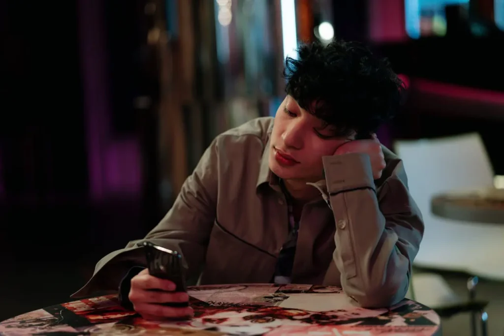 Young app user checking smartphone at café, representing mobile app engagement and monetisation strategies for Malaysian apps