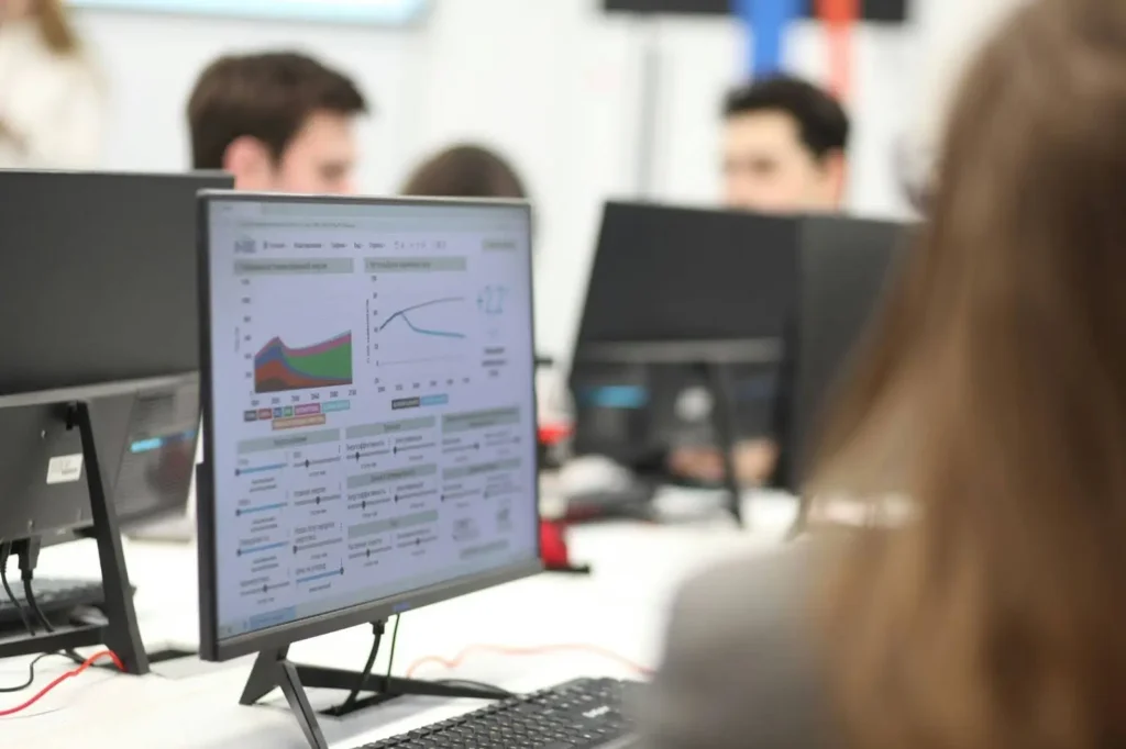 Team analysing data dashboards on computer screens, representing KPI tracking and performance monitoring in software projects.
