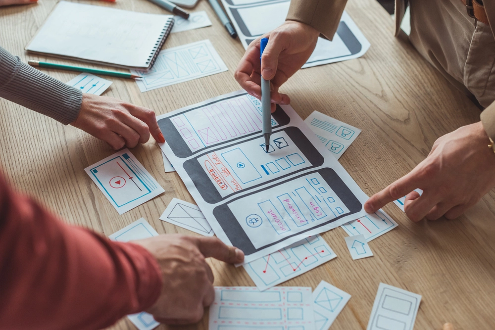 An image showing a two pair of hands arranging papers to arrange an app user journey, represnting the app development method.